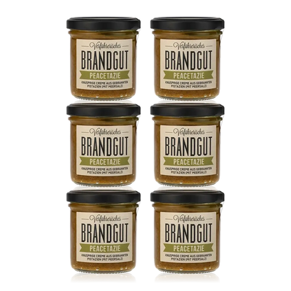 Sechs Gläser Brandgut Peacetazie Pistaziencreme auf weißem Hintergrund.