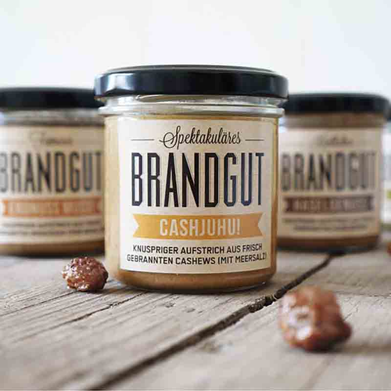 Gläser mit Brandgut Cashew-Aufstrich auf Holztisch.