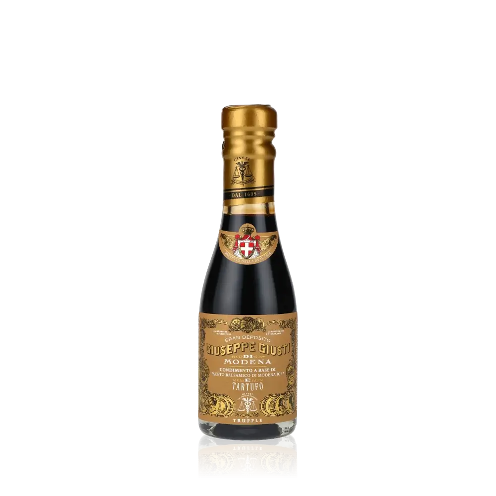 Giuseppe Giusti Trüffel Balsamessig Flasche vor schwarzem Hintergrund.