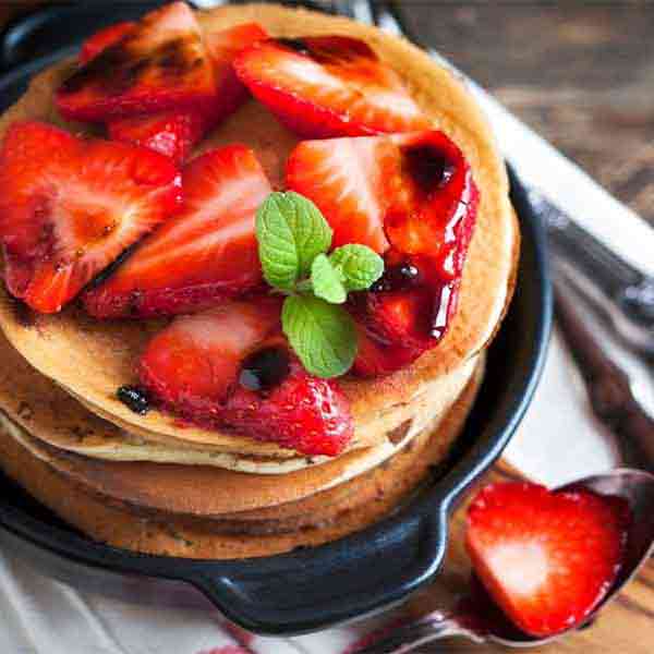 Erdbeeren mit Mussini Balsamico auf Pfannkuchen, Minze garniert.