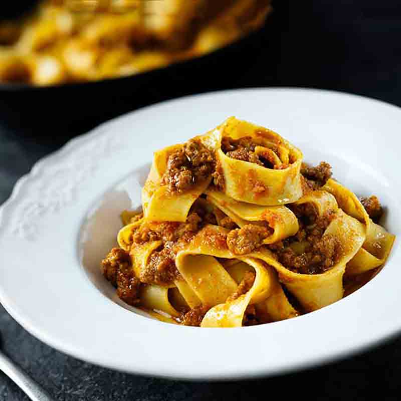 Tagliatelle mit Ragù alla Bolognese, serviert auf einem weißen Teller. Authentische italienische Küche.