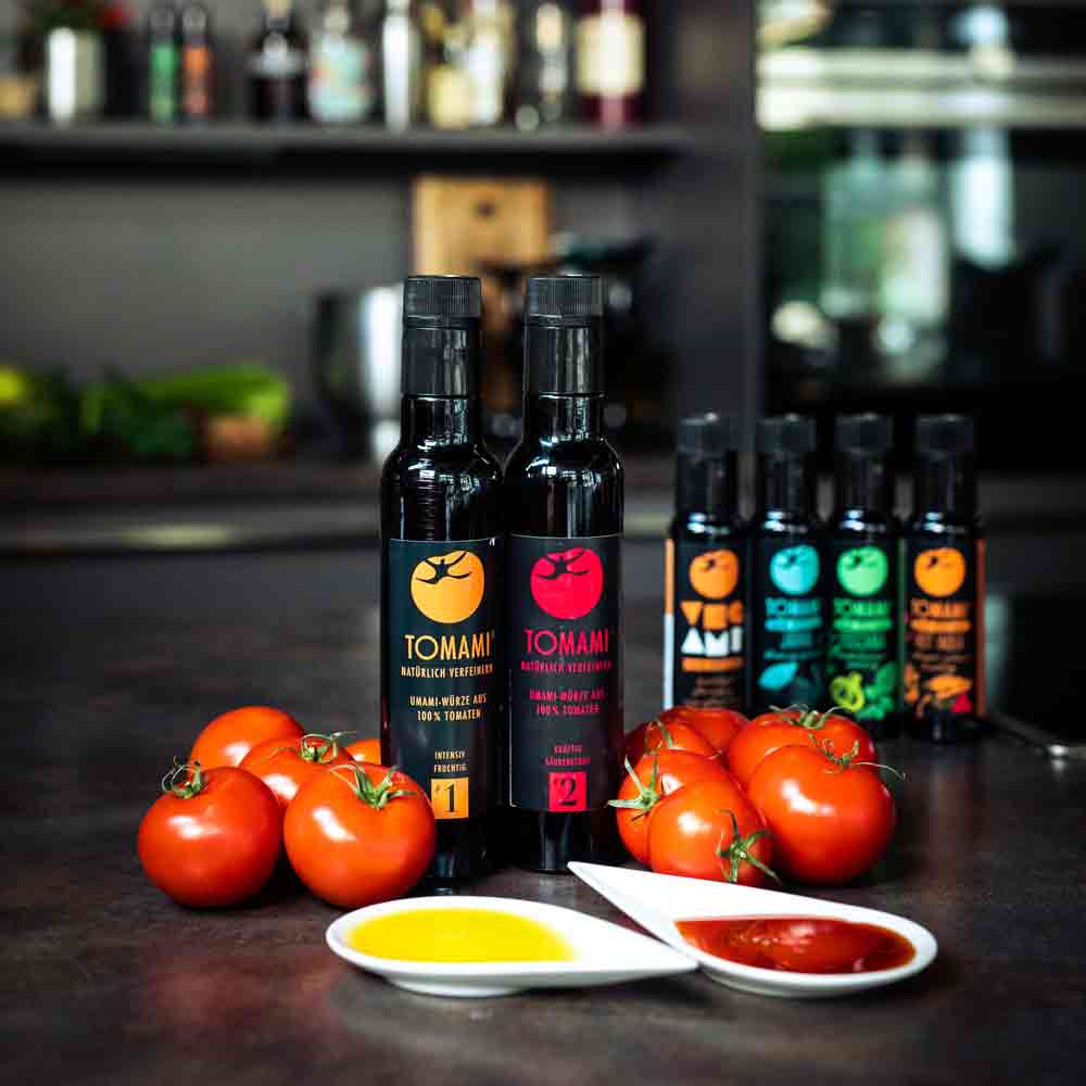 Tomami Flaschen, Tomaten, Olivenöl, Essig, Feinkost auf Tisch.