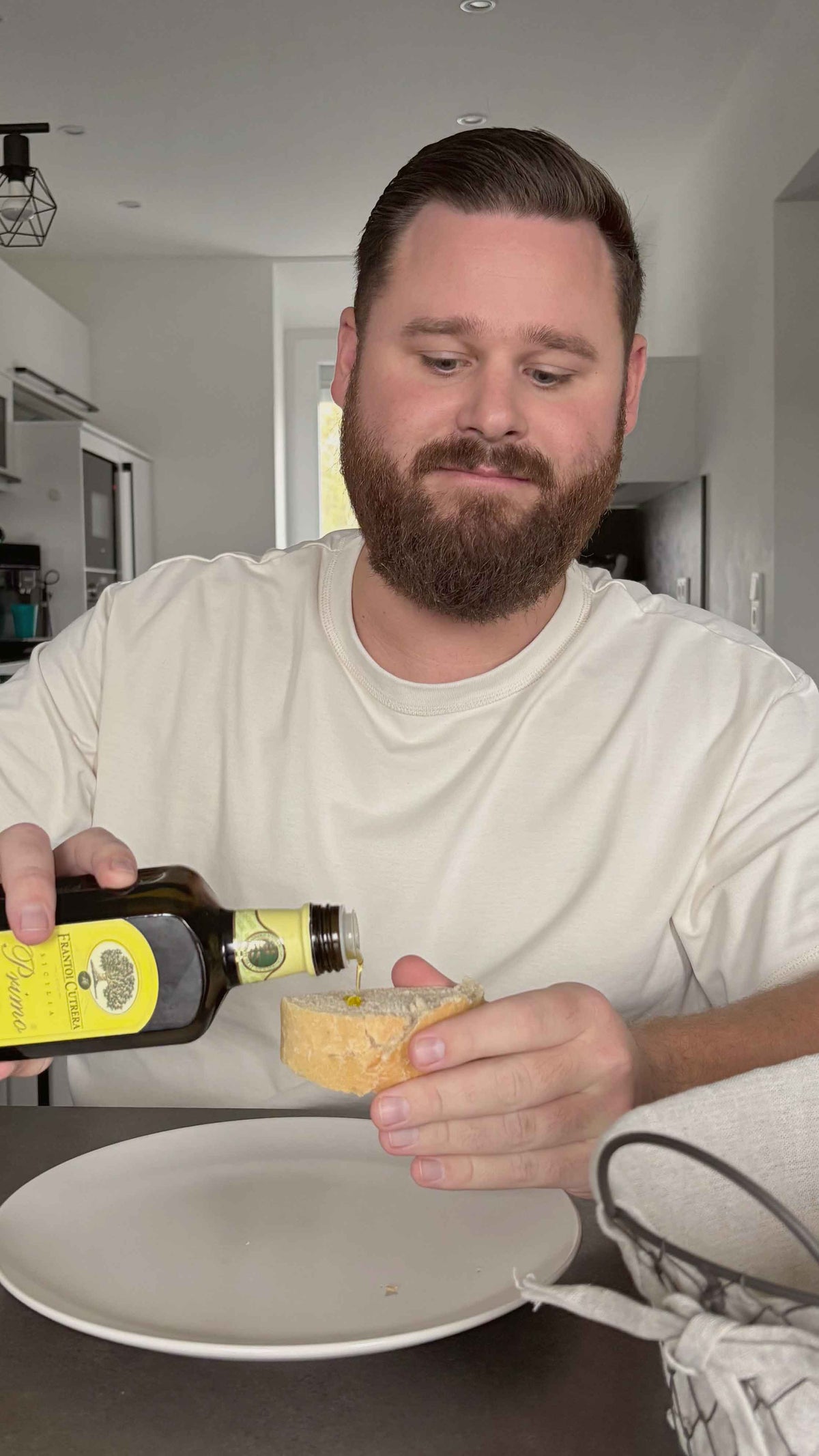 Ein Mann gießt Premium-Olivenöl auf ein Stück Weißbrot