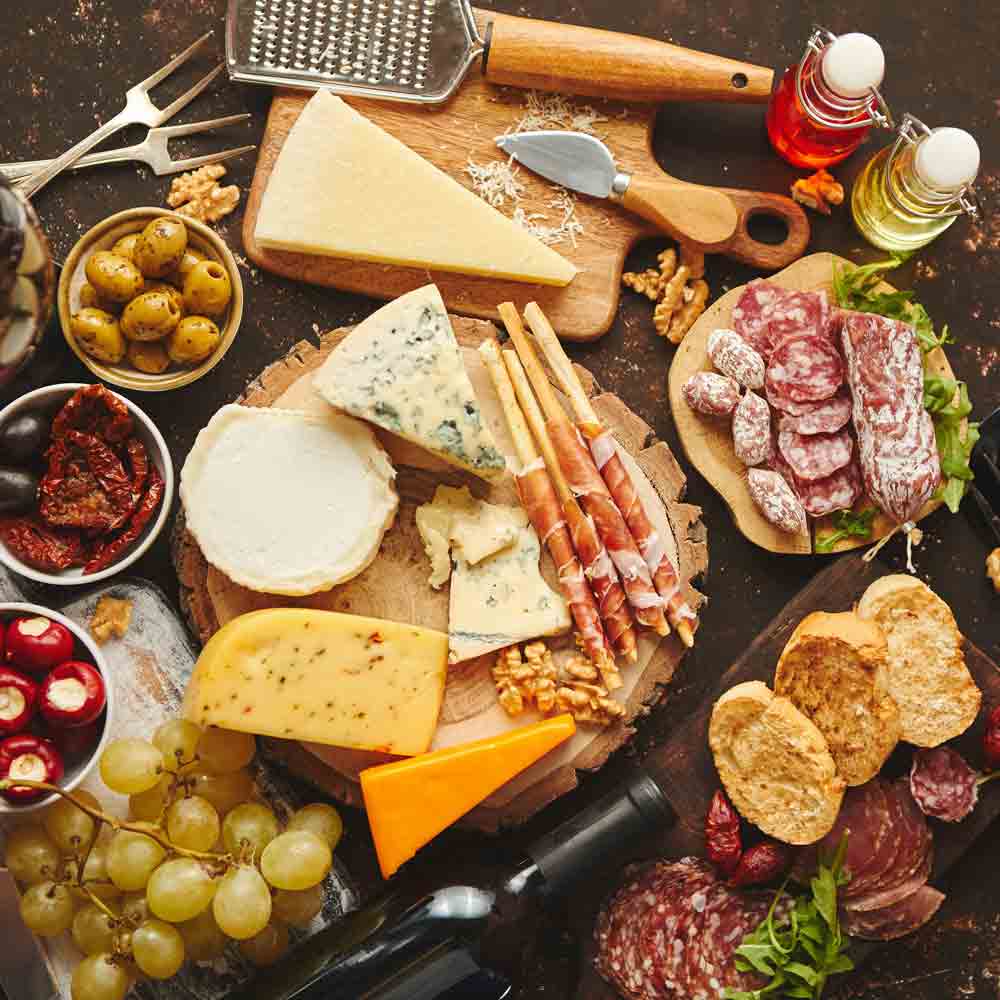 Antipasti mit Käse, Wurst, Oliven, Wein und Essigflaschen.