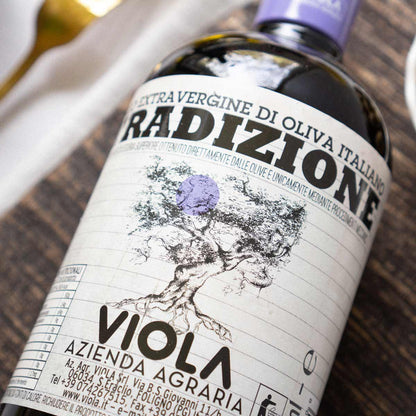Olivenölflasche mit Viola-Etikett auf Holztisch.