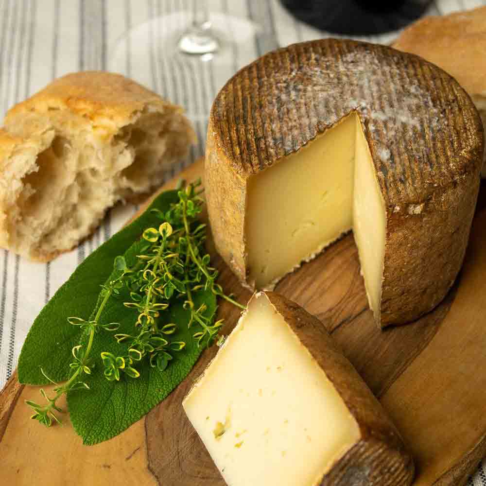 Käse mit Brot und Kräutern auf Holzbrett serviert.