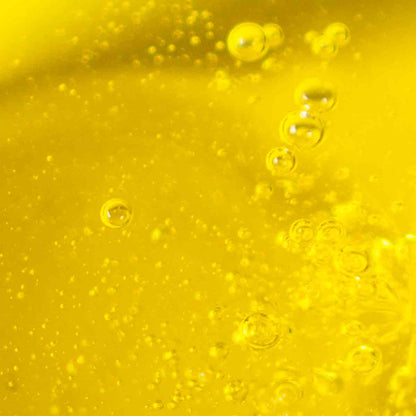 Nahaufnahme von dem goldgelben Olivenöl, dass durch das Eingießen kleine Bläschen mit Luft besitzt.