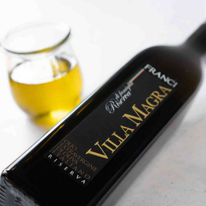 Franci Villa Magra Olivenölflasche und Glas mit Olivenöl.