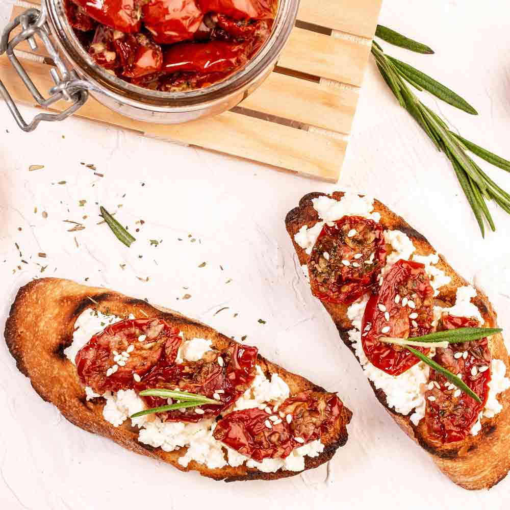 Getrocknete Tomaten auf Brot mit Frischkäse und Kräutern.