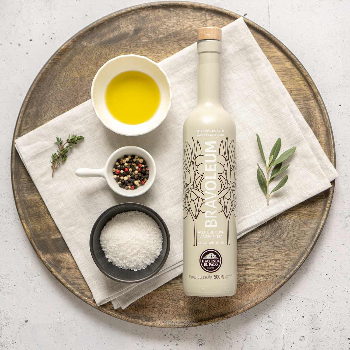 Bravoleum Olivenölflasche mit Gewürzen und Kräutern auf Tablett.
