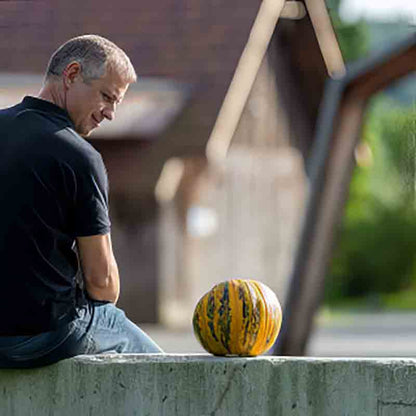Mann betrachtet Kürbis auf Mauer.