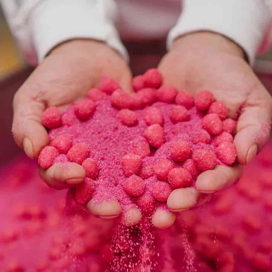 Hände halten rosa Süßigkeiten, Zucker rieselt herunter.