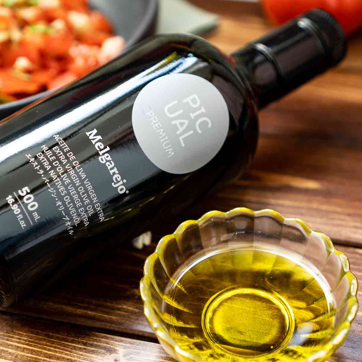 Melgarejo Picual Olivenölflasche und Schale mit Olivenöl.