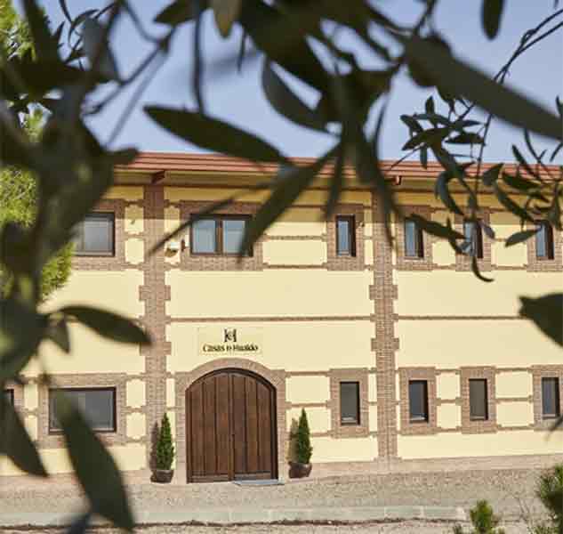 Ölmühle-Gebäude hinter Olivenzweigen.