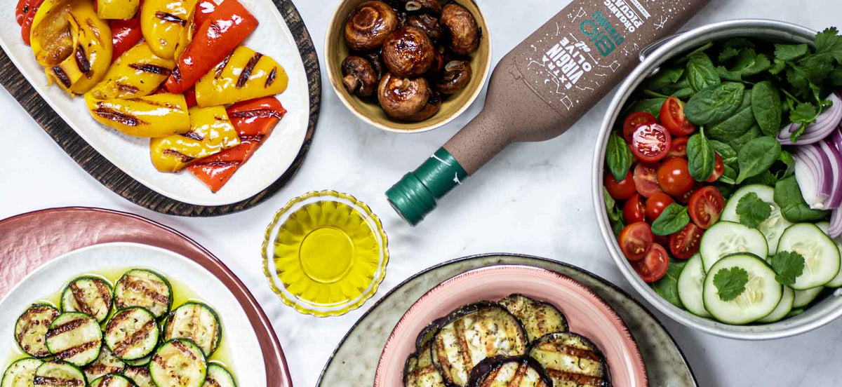 Verschiedene Antipasti mit Olivenöl und Gemüse auf Tellern.