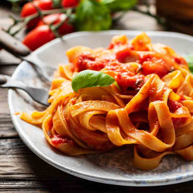 Pasta mit Tomatensauce und Basilikum auf einem Teller.