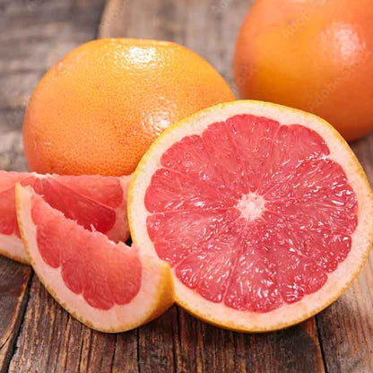 Eine Pink Grapefruit liegt augeschnitten auf einem Tisch. 