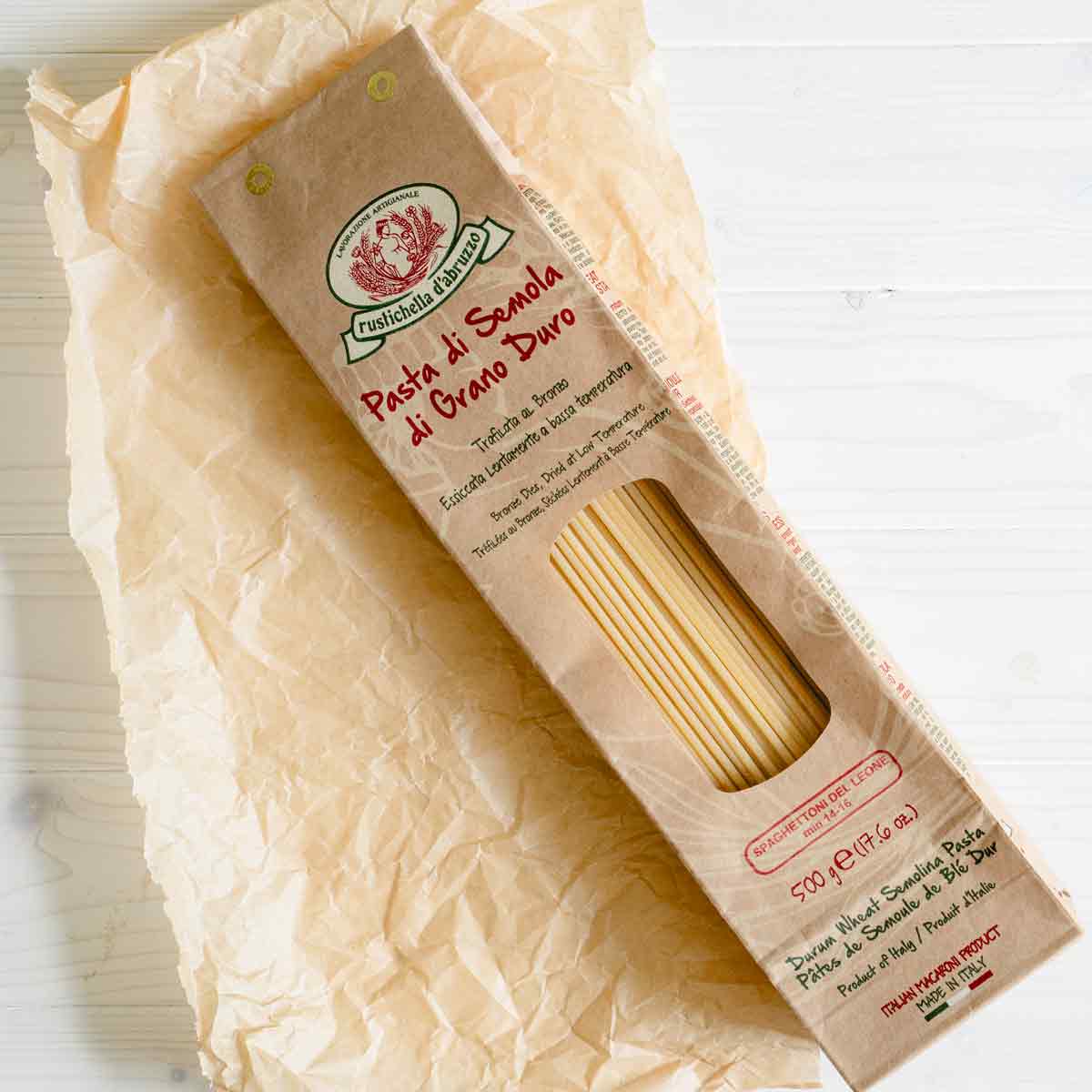 Rustichella Pasta Spaghetti auf Papierunterlage, Verpackung sichtbar.