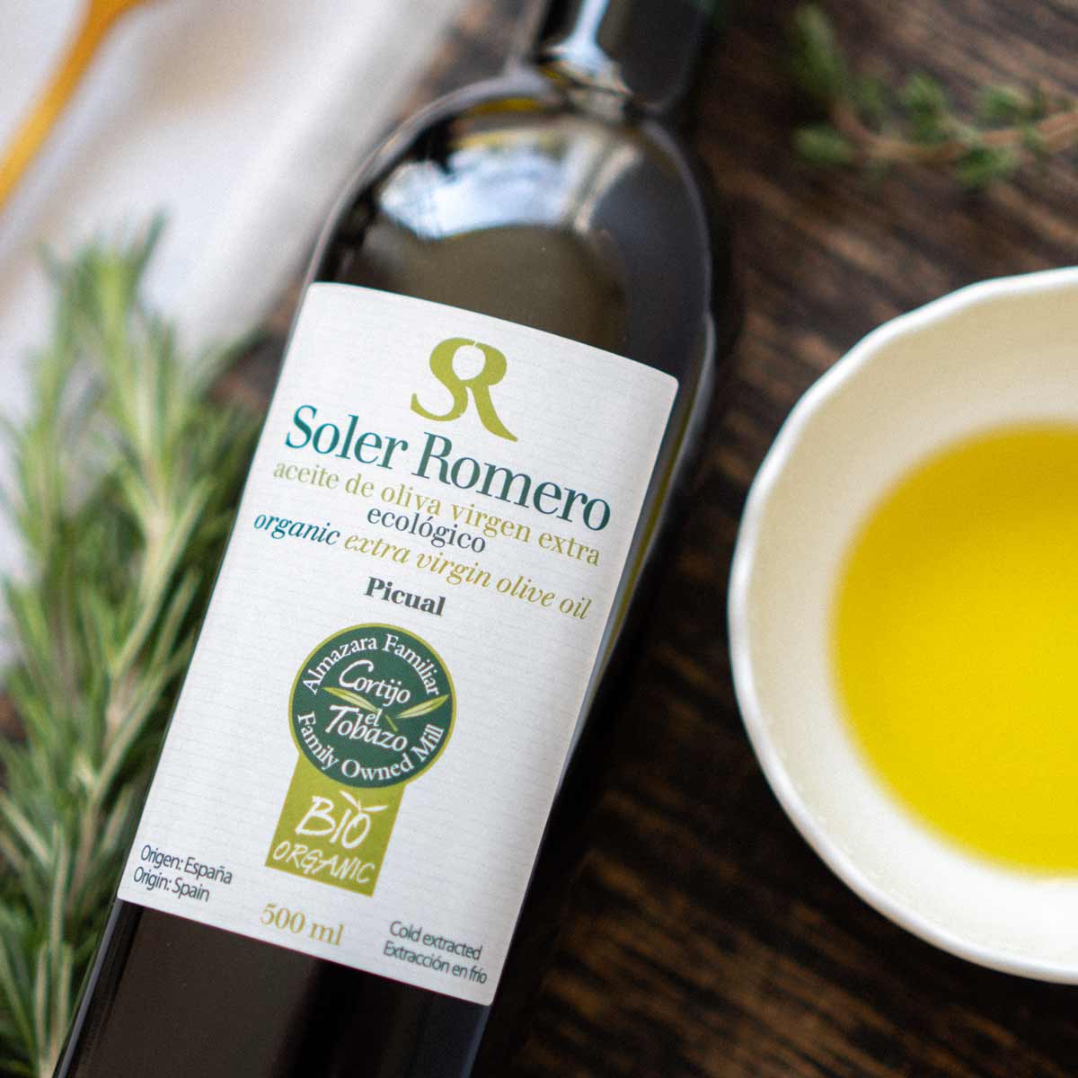 Soler Romero Olivenölflasche neben Schale mit Olivenöl.